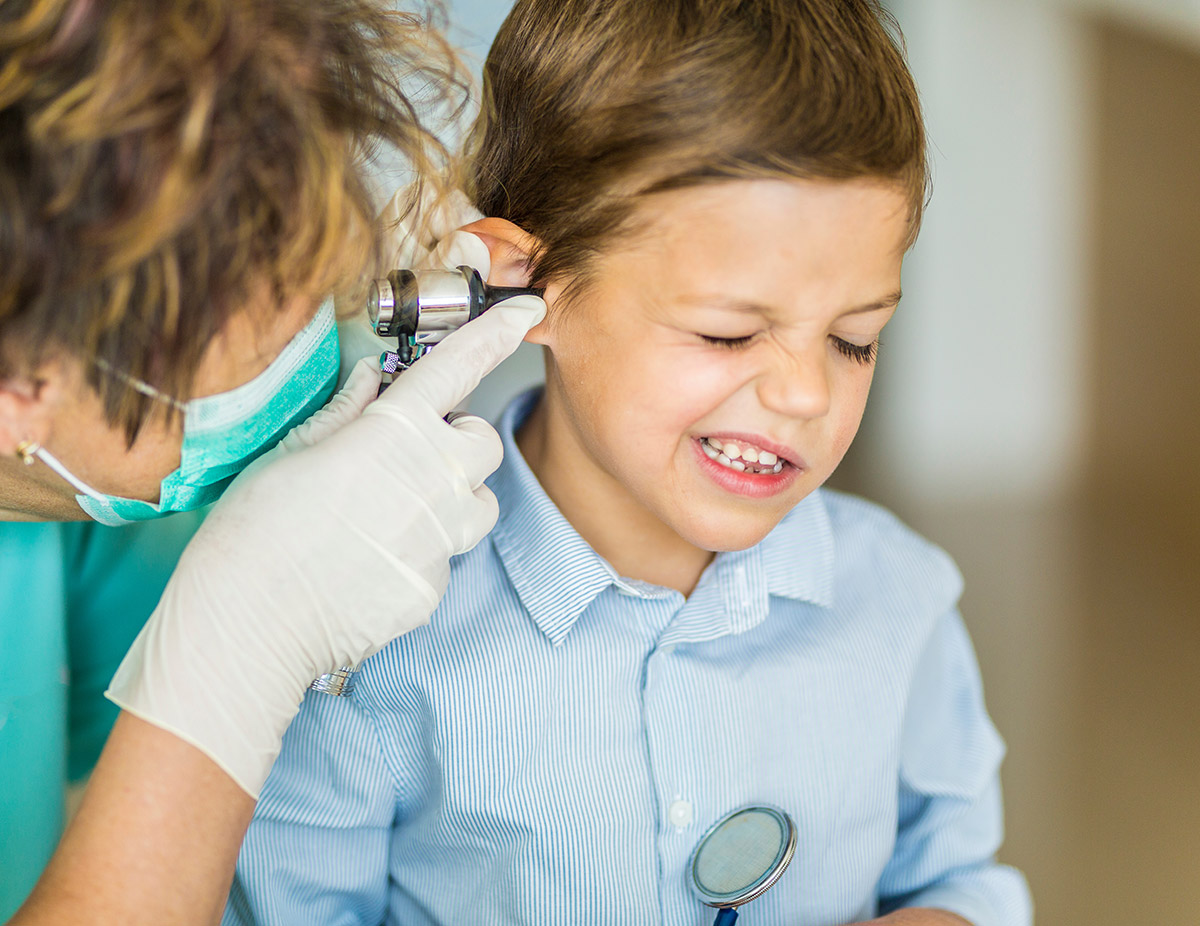 Doctor checking a child's ear, the child has a face of pain