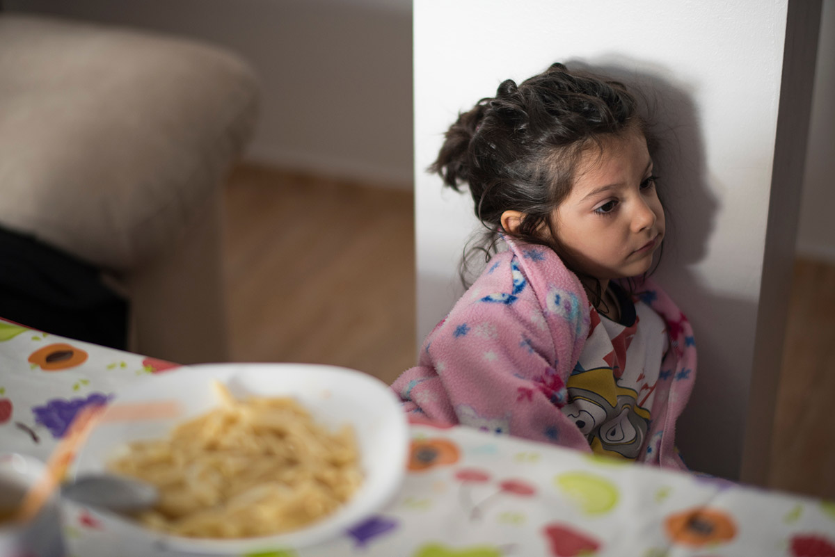 Child looking apathetic, with a rejected bowl of food in the foreground